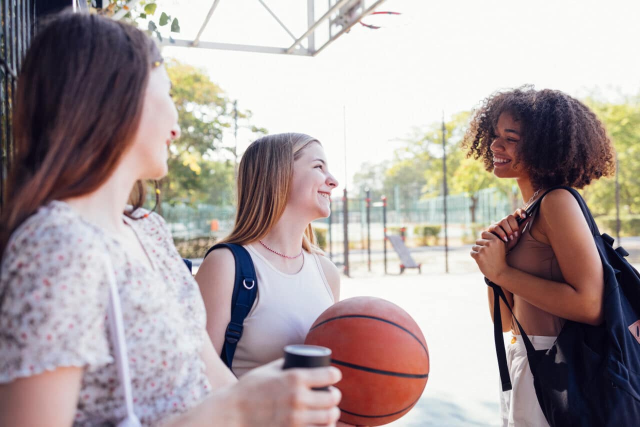 tylish cool teen girls gathering at basketball court, friends ready for playing basketball outdoors