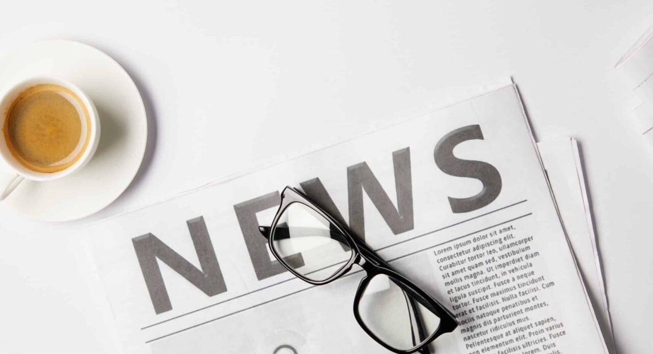 flat lay with eyeglasses, cup of coffee and newspapers, on white