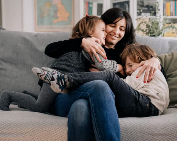 Image of Caregiver (Parents) embracing adopted/foster children.